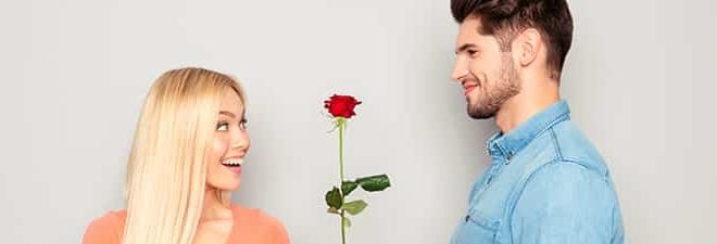 Mann hat ein Kompliment für eine Frau und schenkt ihr eine Rose.