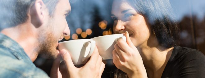 Mann und Frau halten Blickkontakt mit Kaffee in der Hand