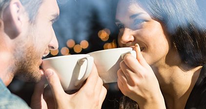 Mann und Frau halten Blickkontakt mit Kaffee in der Hand