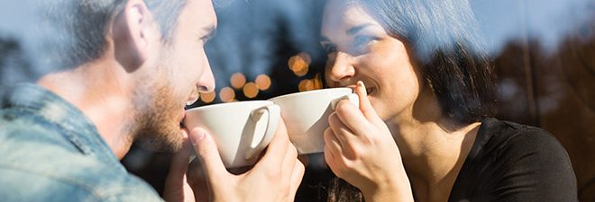 Mann und Frau halten Blickkontakt mit Kaffee in der Hand