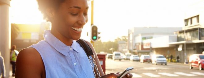 Mingle: Frau auf der Straße schaut auf Handy