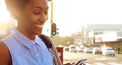 Mingle: Frau auf der Straße schaut auf Handy