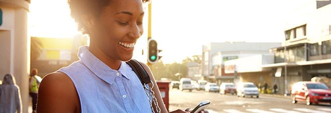 Mingle: Frau auf der Straße schaut auf Handy