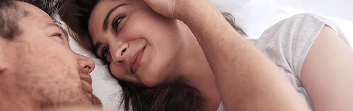 Sex beim ersten Date: Mann und Frau liegen im Bett und schauen sich an