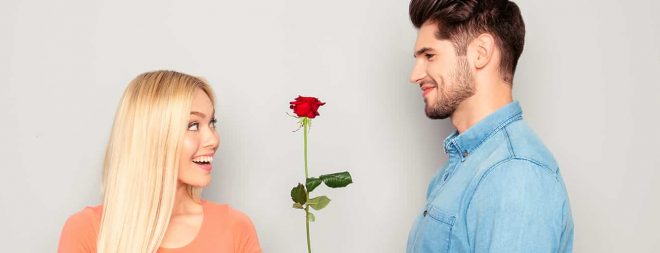 Mann hat ein Kompliment für eine Frau und schenkt ihr eine Rose.