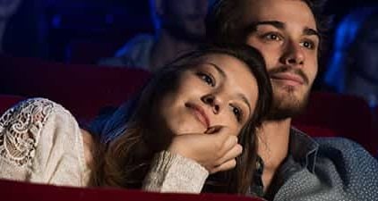 Frau lehnt an Schulter des Mannes beim Date im Kino.