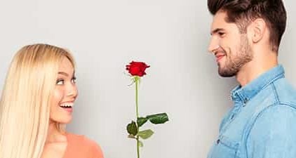 Mann hat ein Kompliment für eine Frau und schenkt ihr eine Rose.