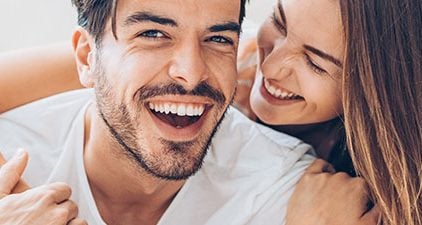 Mann und Frau lächeln sich an, als Zeichen für eine glückliche Beziehung