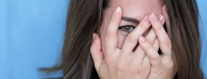 Frau hat Angst vor dem ersten Date - hält sich die Hände vors Gesicht