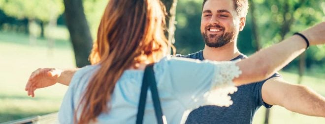 Frau und Mann laufen zur Begrüßung beim ersten Date mit offenen Armen auf sich zu.