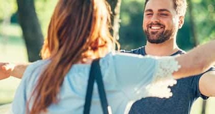 Frau und Mann laufen zur Begrüßung beim ersten Date mit offenen Armen auf sich zu.