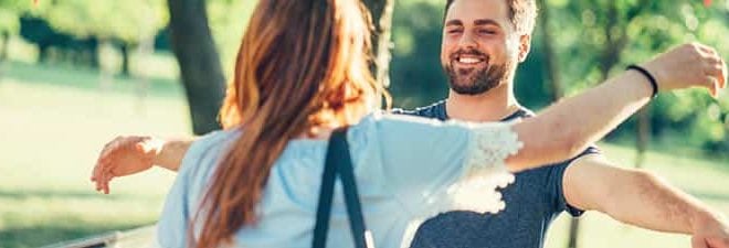 Frau und Mann laufen zur Begrüßung beim ersten Date mit offenen Armen auf sich zu.