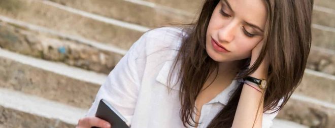 Eifersüchtig auf Ex: Frau schaut nachdenklich auf das Handy