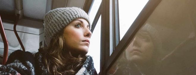 Frau sitzt in der Bahn, schaut aus dem Fenster und fragt sich "Vermisst er mich?"