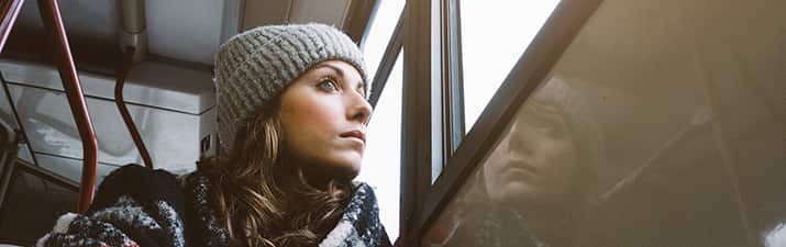 Frau sitzt in der Bahn, schaut aus dem Fenster und fragt sich "Vermisst er mich?"