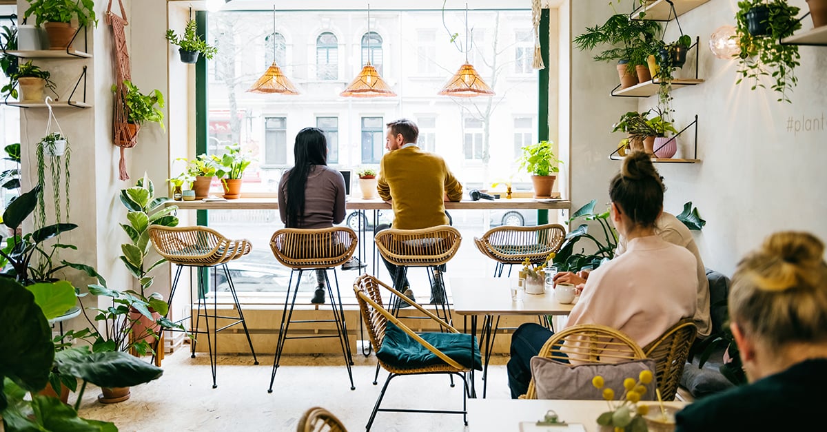 Frau und Mann sitzen gemeinsam in einem Café am Fenster.