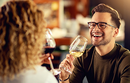 Mann mit Brille trinkt Weißwein und lacht