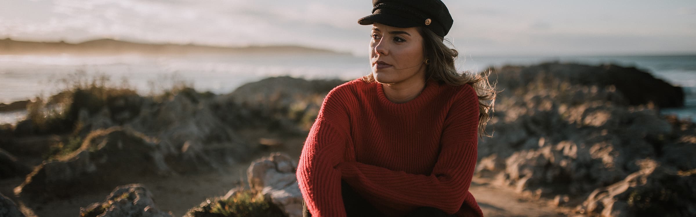 Sitzende Frau mit maritimer Mütze und rotem Pullover