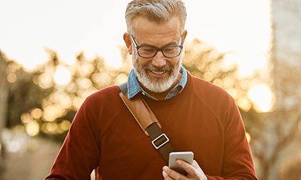 Ein Mann über 50 schaut glücklich auf sein Handy