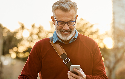 Ein Mann über 50 schaut glücklich auf sein Handy