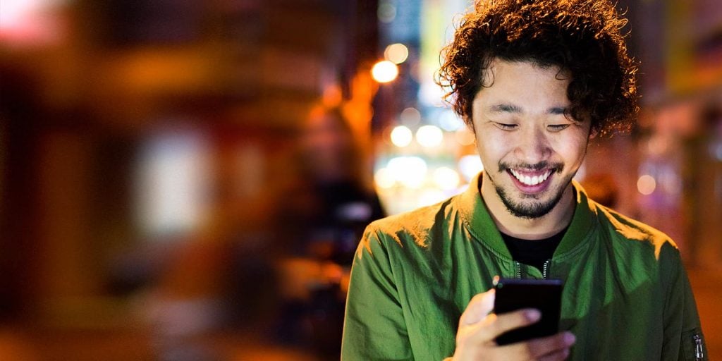 Mitgliedschaft bei Parship: Mann lächelt mit Handy in der Hand