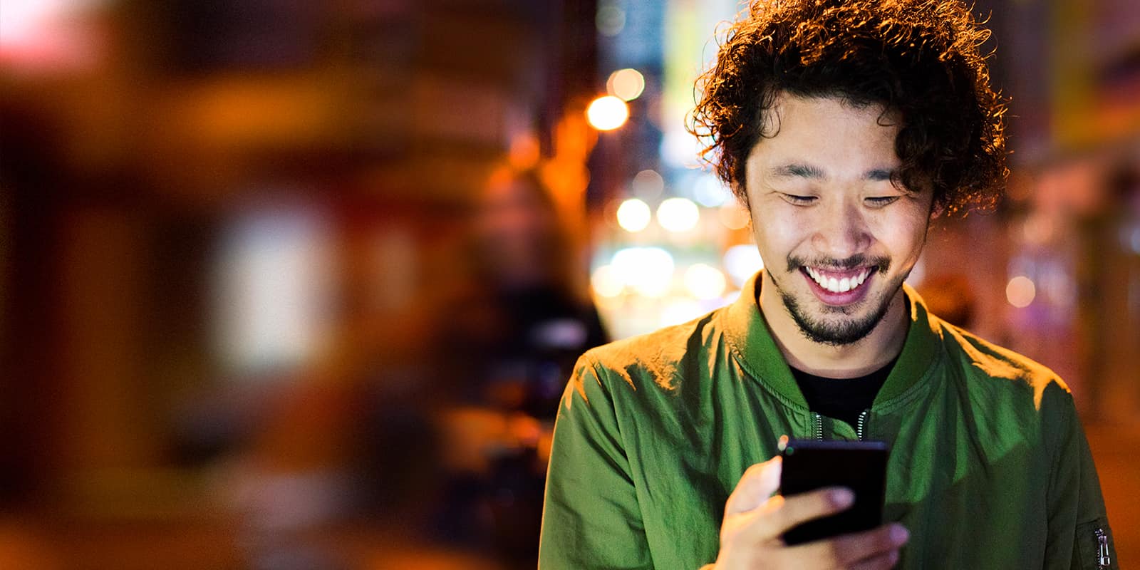 Mitgliedschaft bei Parship: Mann lächelt mit Handy in der Hand