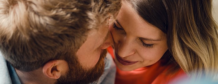 Mann und Frau berühren lächelnd ihre Gesichter