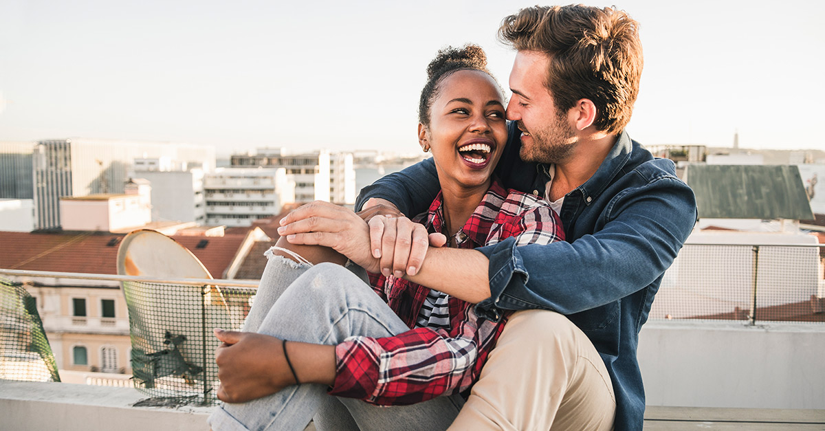 Paar sitz auf Dachterrasse, Arm in Arm, lachend