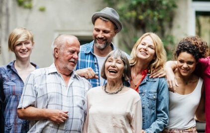 Eine Familie mit älteren und jüngeren Menschen steht gut gelaunt zusammen - von ihnen wird ein Foto gemacht.