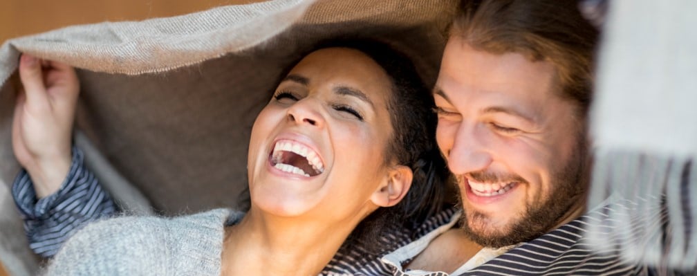 Frau und Mann liegen sich in den Armen und lachen